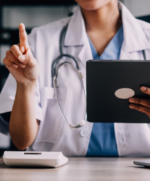 Concerned young female Caucasian doctor in white medical uniform sit at desk in hospital work on laptop, focused woman nurse or GP busy fill anamnesis on computer gadget, medicine, technology concept