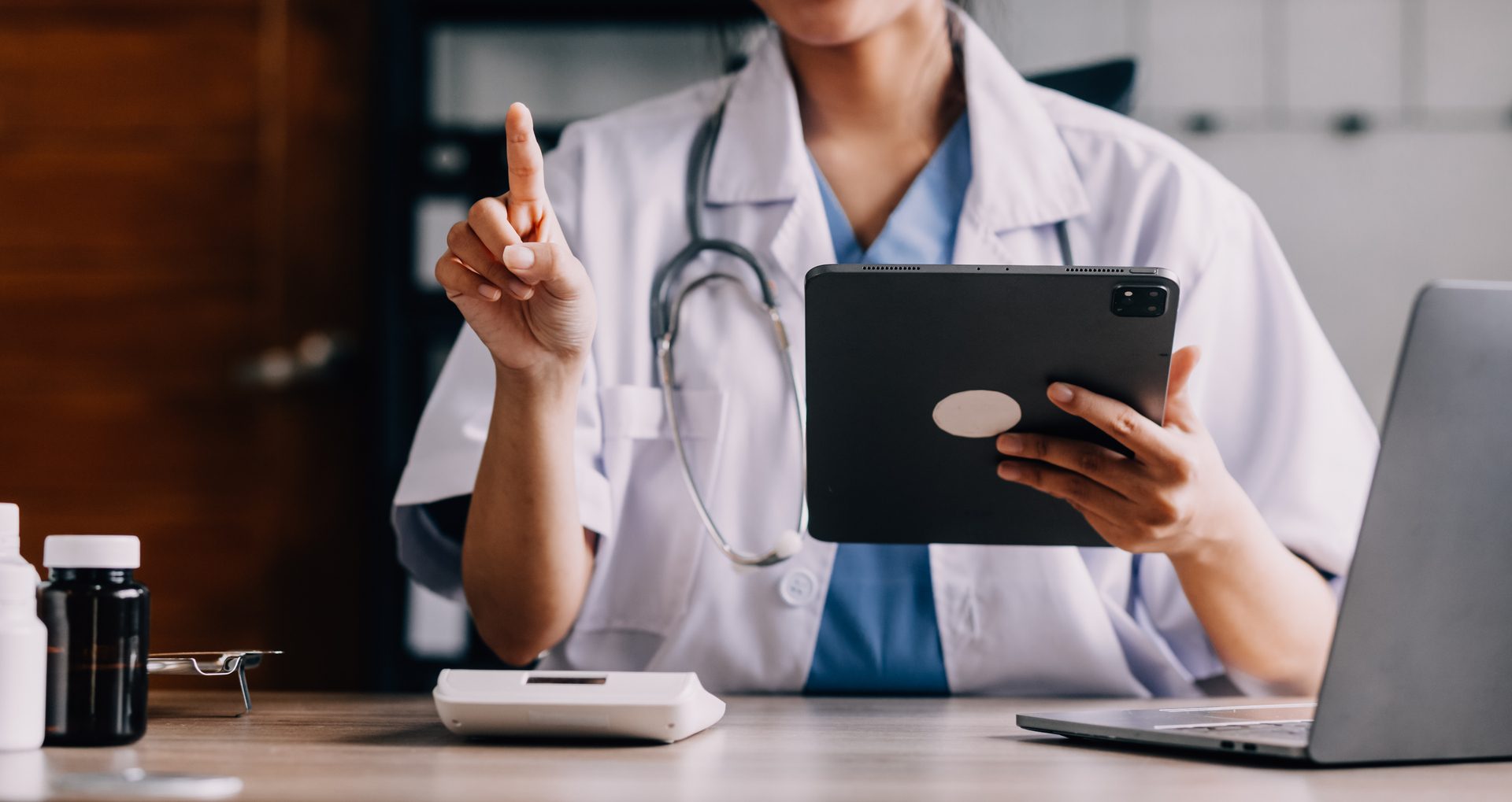 Concerned young female Caucasian doctor in white medical uniform sit at desk in hospital work on laptop, focused woman nurse or GP busy fill anamnesis on computer gadget, medicine, technology concept
