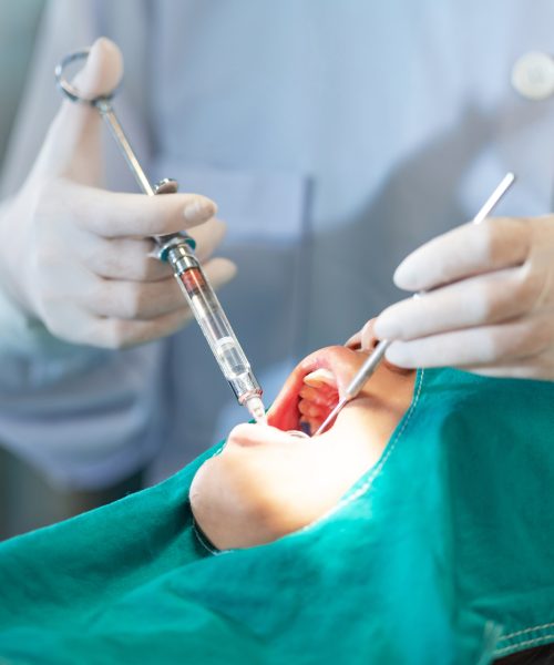 Female dentist standing in dentist office work with light-curing seal, Close up of dentist's hands with assistant in white gloves are treating teeth to a girl