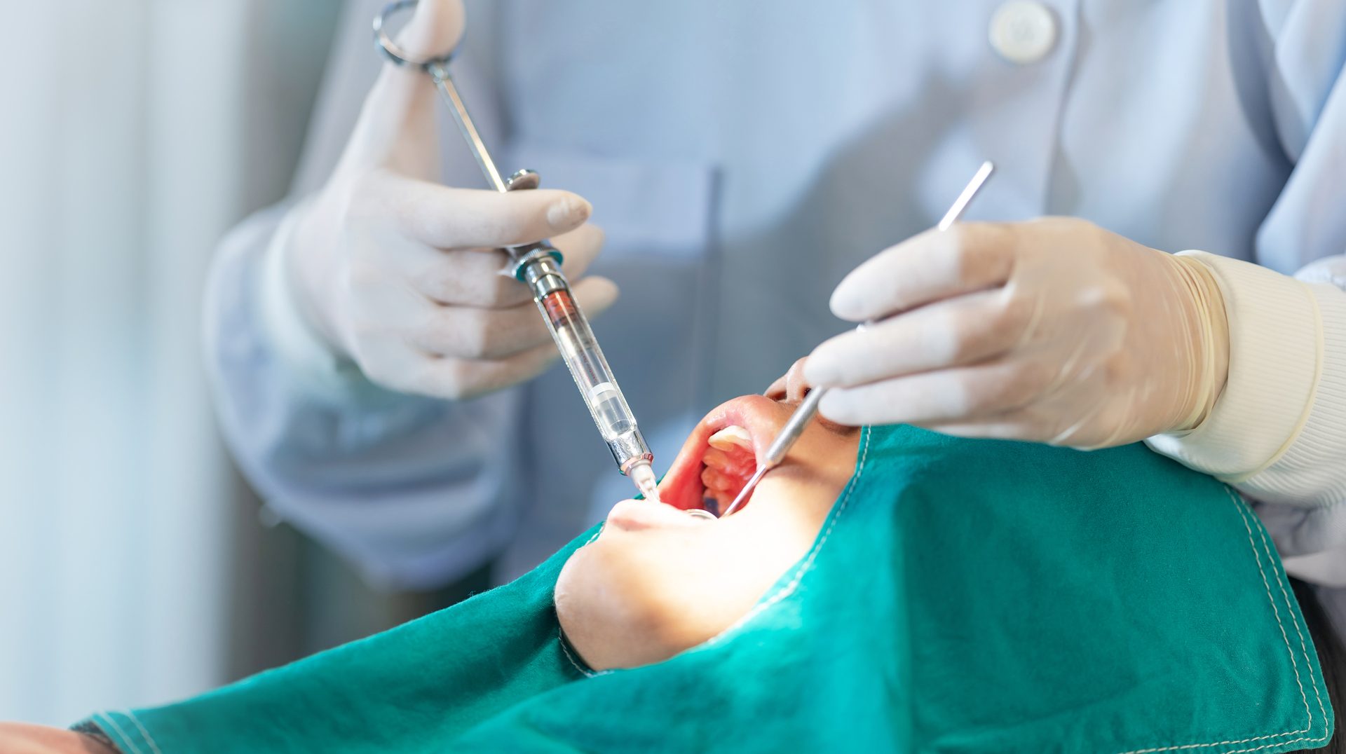 Female dentist standing in dentist office work with light-curing seal, Close up of dentist's hands with assistant in white gloves are treating teeth to a girl