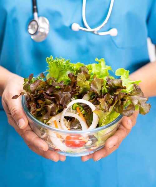Nutritionist doctor holding various healthy fresh vegetables for patient.