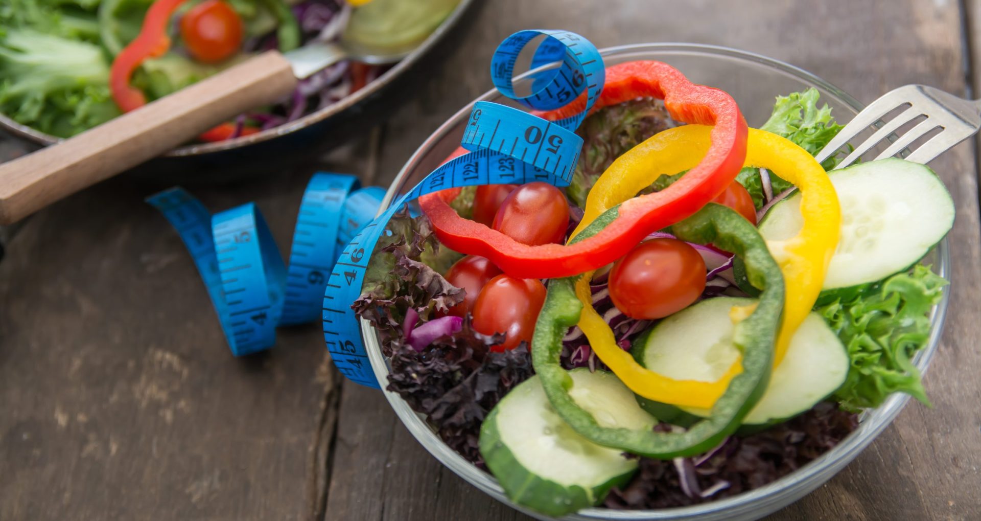 Fresh vegetables salad on  bowl with measuring tape over wooden background. Diet Food and healthy lifestyle concept.
